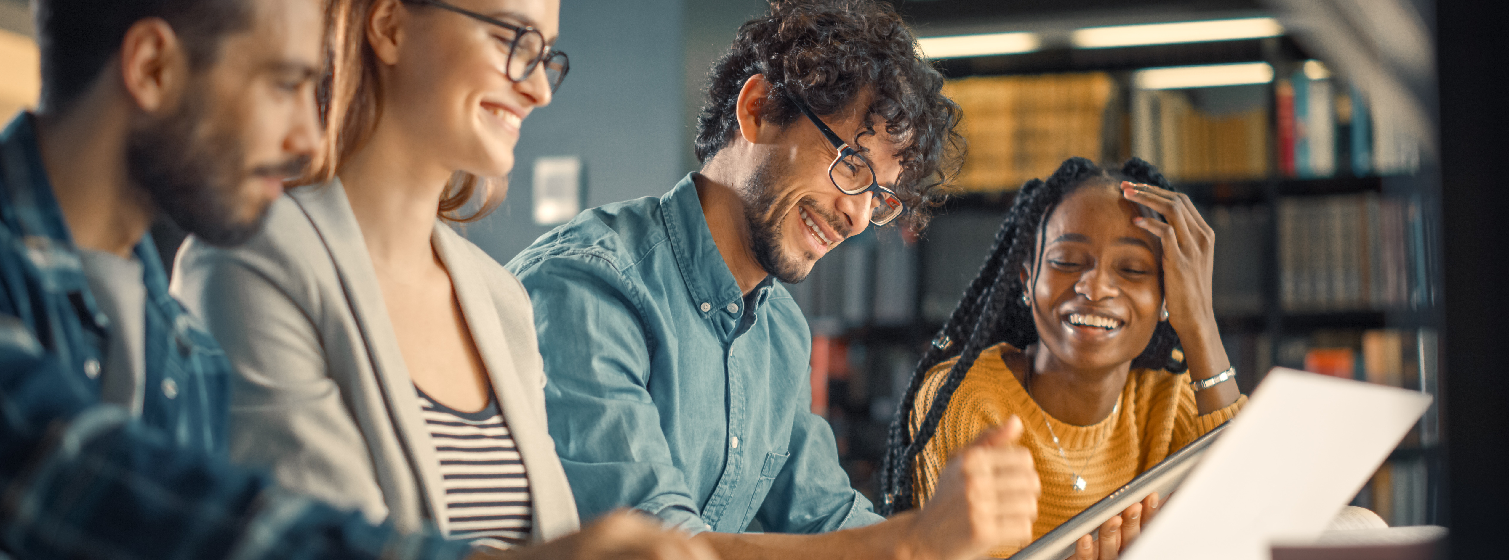 An instructor and students work at a laptop and smile.