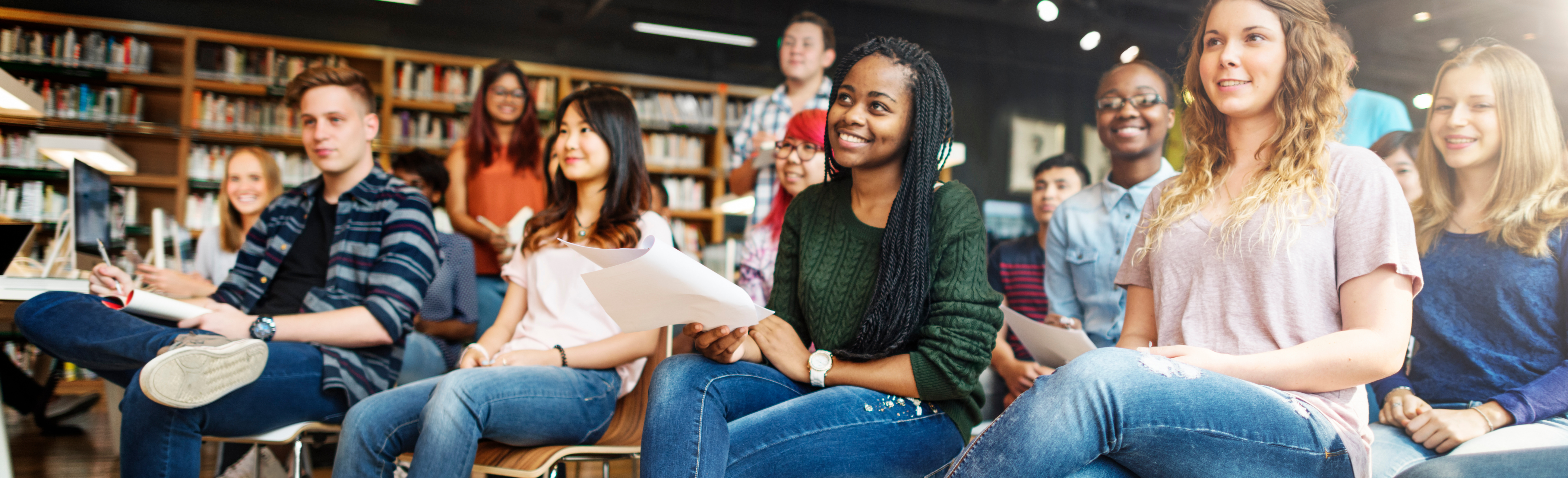 College students smile while looking toward the front of class.