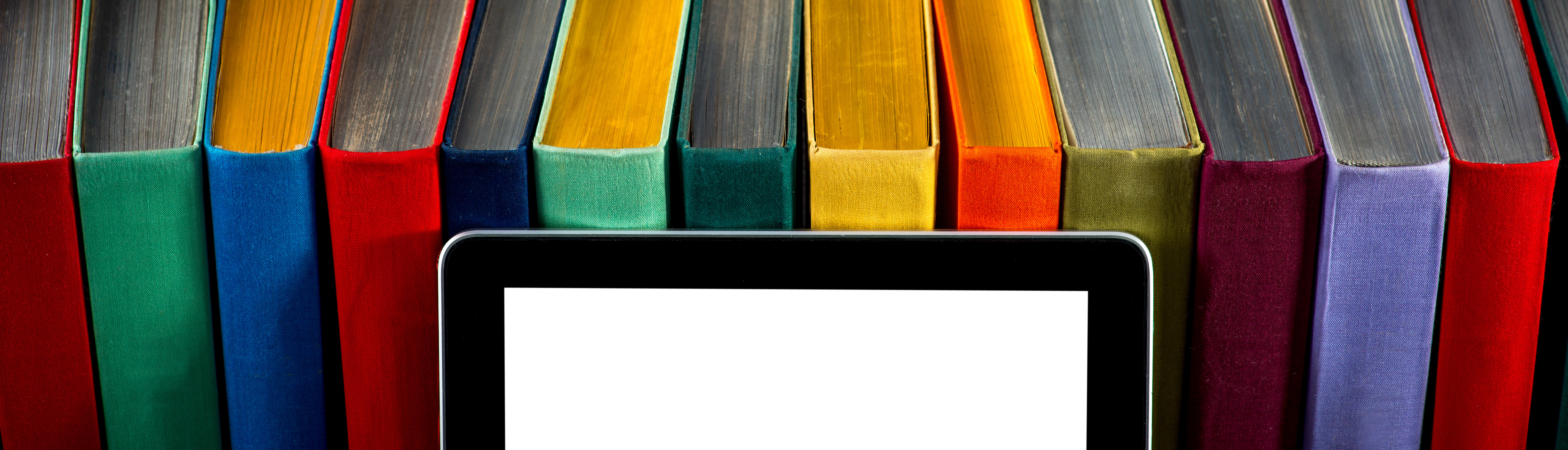 A tablet sitting in front of a row of colored books