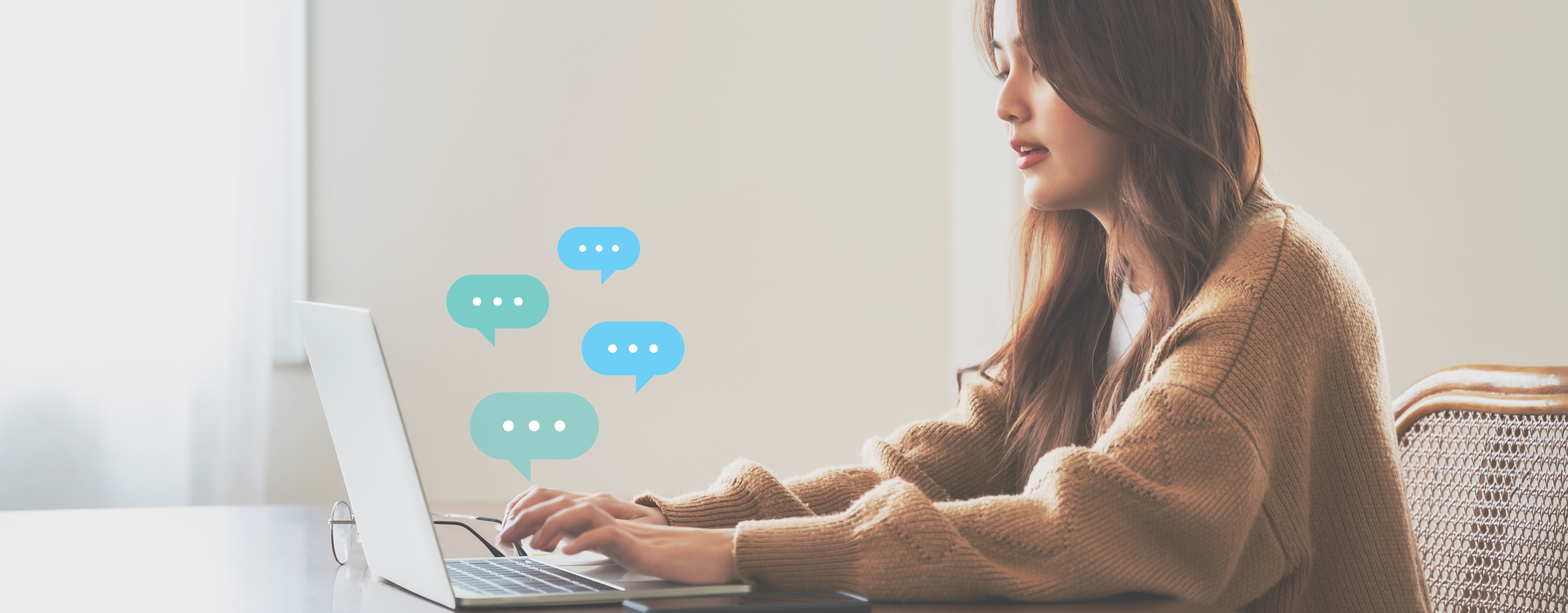 A student types on a laptop from which illustrated chat bubbles are rising.