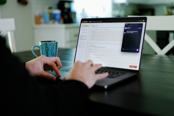 Hands typing on a laptop, an AI chat is visible on the screen