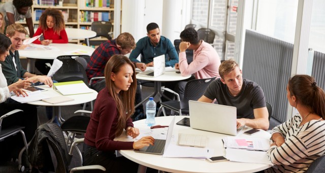 Groups of students working a four different tables. 