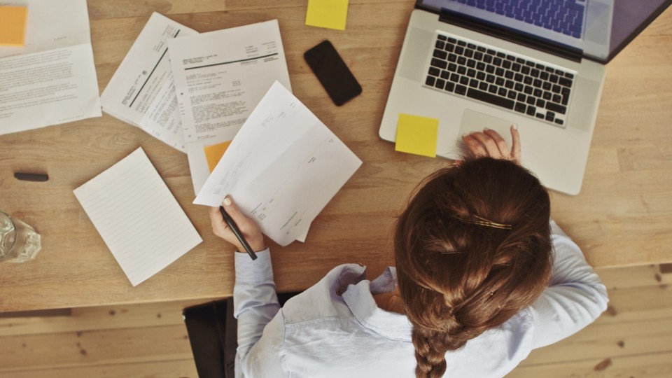 Female student on a laptop surrounded by papers