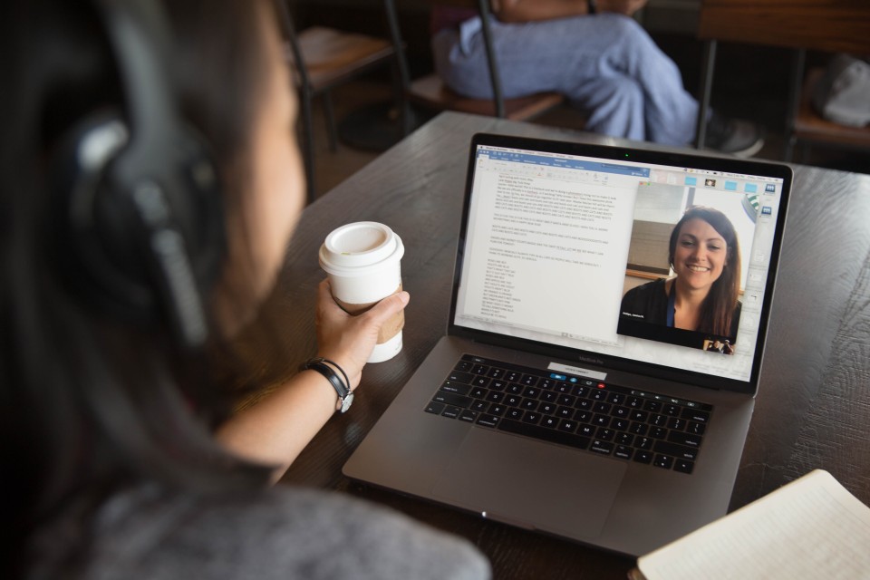 Student in coffee shop in a virtual meeting on laptop