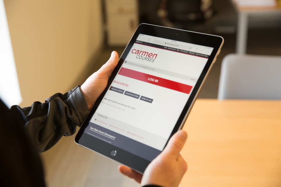 Person holding iPad with CarmenCanvas login page on screen