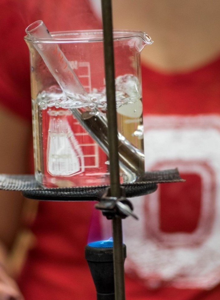 Lab beaker with blurred person in background