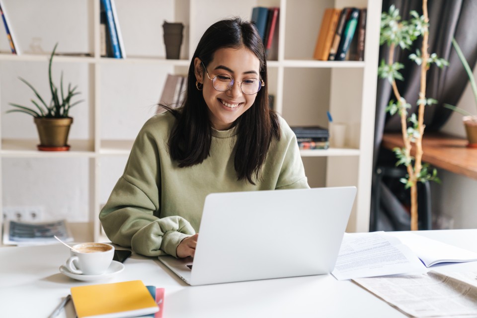 A smiling student works on a laptop.