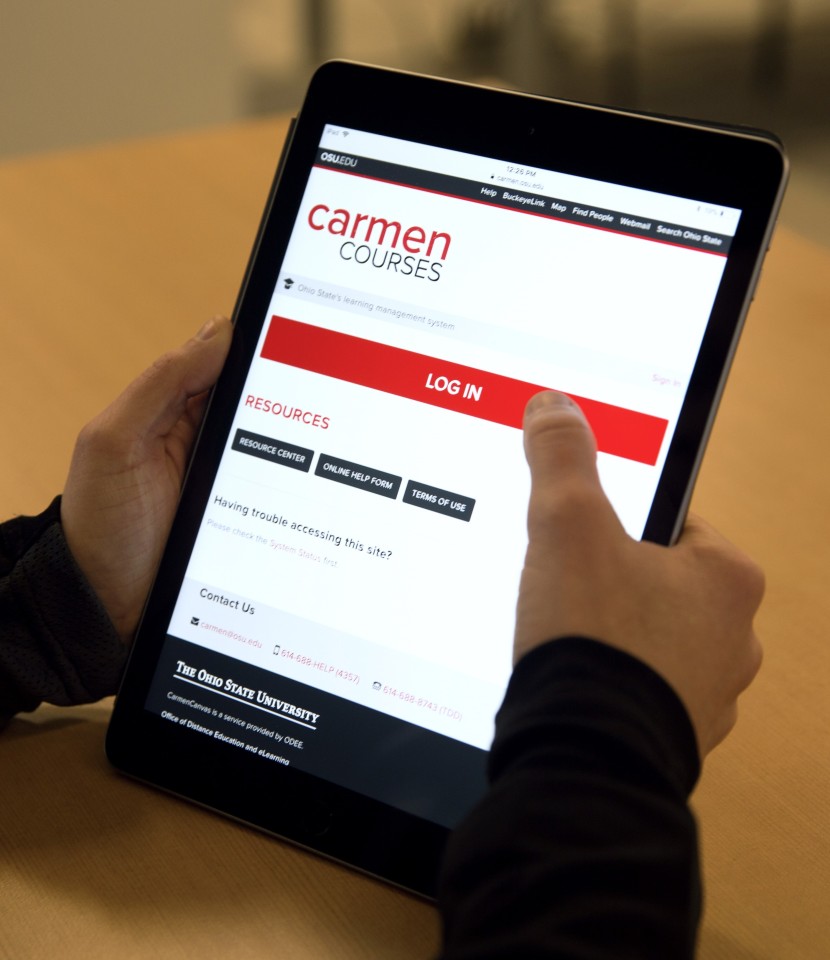 User holding iPad with Carmen login on the screen. 
