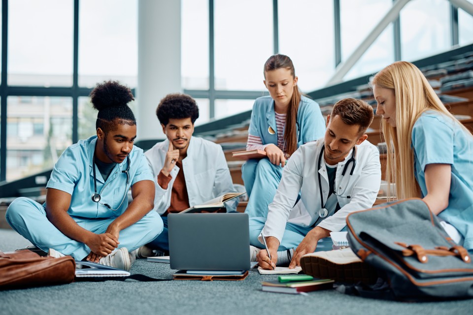 Medical students working on something on the floor of a lecture hall.