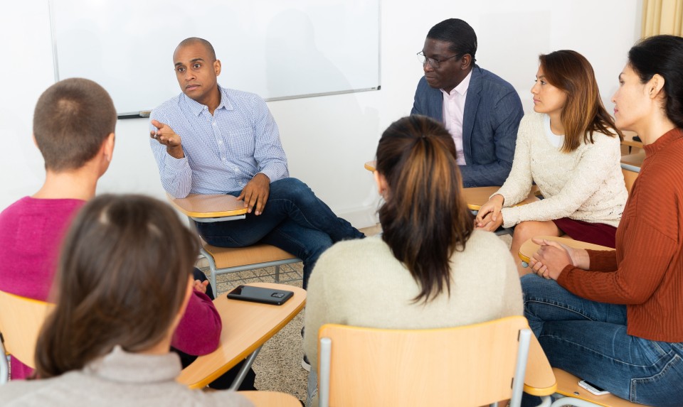 Students meeting in a small group, with their desks in a circle.