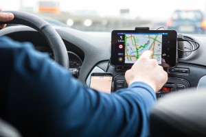 A driver's finger touching a car's GPS navigation touch screen.